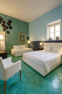 a large bedroom with two beds and a chair at Suites Edivino Design Capri in Capri