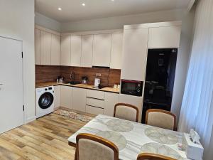 a kitchen with a table with chairs and a kitchen with white cabinets at Rooftop 1 Bedroom, Near City Center in Ulaanbaatar