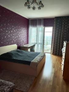 a bedroom with a bed and a desk and a window at Апартаменты на набережной с панорамным видом на 39 этаже in Astana