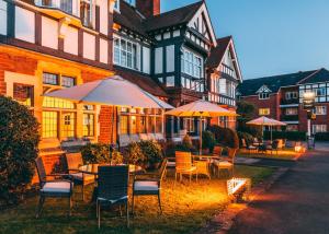 een groep tafels en stoelen met parasols voor een gebouw bij Colwall Park - Hotel, Bar & Restaurant in Great Malvern