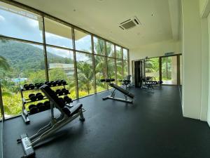a gym with treadmills and machines in a room with windows at By The Sea with Side Seaview #363A in Batu Ferringhi