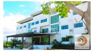 a white building with blue windows and a tree at Kosit One Hotel in Ban Bung Sam Phan Nok