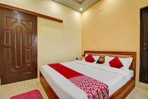 a bedroom with a bed with red pillows and a door at Hotel O The Honey Guest House in Haldwāni