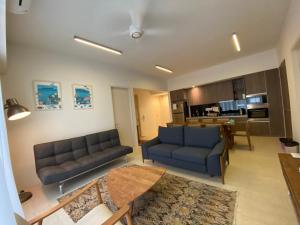 バトゥ・フェリンギにあるBy The Sea Luxury Beachfront Resort 223の青いソファ2つとテーブルのあるリビングルーム