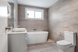 a bathroom with a tub and a toilet and a sink at Sleek & Comfortable Double Room at Revesby with Shared Amenities in Revesby +24 photos