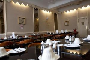 a dining room with tables and chairs with white napkins at Rose Court Hotel in London