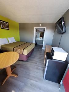 a hotel room with two beds and a tv and a table at Lamplighter Inn Independence in Independence