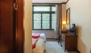 a hotel room with a bed and a tv and a window at James Joyce Coffetel Xian Dayanta Metro Station Branch in Xi'an
