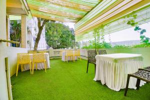 a room with tables and chairs with green grass at FabExpress Royal Baga Residency - 500m From Baga Beach in Old Goa +21 photos