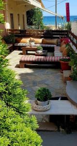 a patio with couches and potted plants and the beach at Seaside Apartments & Rooms Kampouri in Stómion