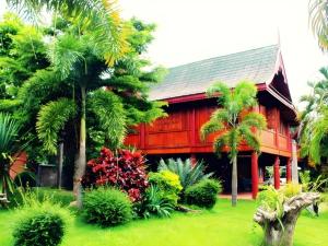 una casa rossa con palme di fronte di Umphangburiresort a Umphang