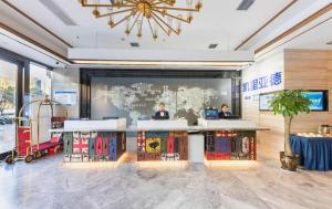 two people sitting at a desk in a room with a large screen at Kyriad Marvelous Hotel·Xi'an North High-speed Railway Station in Xi'an