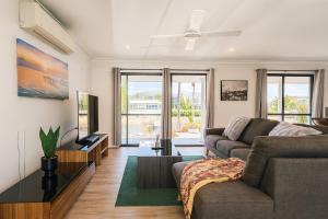 a living room with a couch and a tv at Stillwater Getaway - Waterfront House with Pontoon in Gold Coast