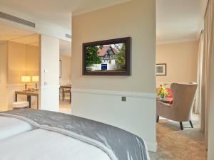 a bedroom with a bed and a tv on the wall at Dorint Hotel Frankfurt/Oberursel in Oberursel