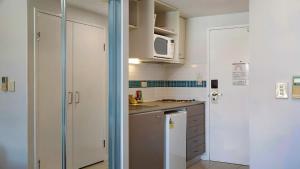 a kitchen with white cabinets and a microwave at Vista Mare - Beachside Studio With Stunning Views in Ettalong Beach +5 photos