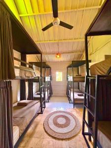 a room with several bunk beds with a ceiling fan at One More Wave Surf House Uluwatu in Uluwatu