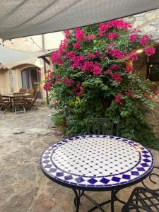 a table and chairs in front of pink flowers at Charming village house for families & cyclists in Juià