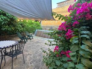 a patio with a table and chairs and pink flowers at Charming village house for families & cyclists in Juià