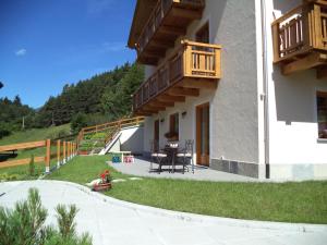 ein Haus mit einer Terrasse mit einem Tisch und einem Balkon in der Unterkunft SoleLuna in Valdidentro