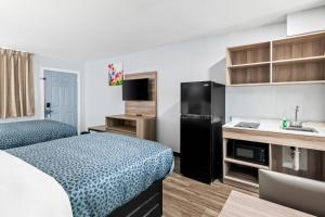 Una pequeña habitación de hotel con una cama y un lavabo. en Suburban Studios Harvey - New Orleans, en Harvey