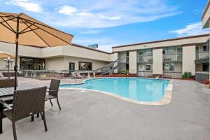 una piscina in un hotel con sedie e ombrellone di Suburban Studios Harvey - New Orleans a Harvey