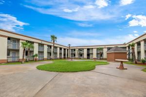 un grande edificio con cortile con palme di Suburban Studios Harvey - New Orleans a Harvey