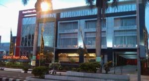 a large building with palm trees in front of it at Grand Dian Hotel Slawi in Procot