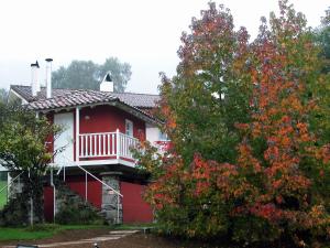 a red house with a white porch and a tree at La Posada de Babel in Llanes