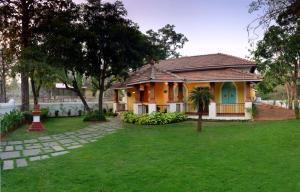 a small yellow house with a green yard at ELIVAAS Terra Rosa Portuguese-styled 4-BHK Villa With Private Pool, Garden, Veranda & Sit-out Area in Vainguinim