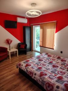 a bedroom with a bed and a red wall at Стаи за гости - Цветето на Ангела in Bankya +52 photos