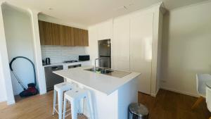 a kitchen with a white counter and stools in it at Residence Of Frankcom in Blackburn