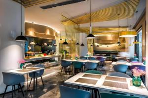 a restaurant with tables and chairs and a kitchen at ibis Styles Yangzhou Baixiang Rd Hotel in Yangzhou