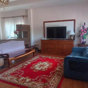 a living room with a tv and a couch and a red rug at Baan Farang in Ban Nong Chaeng