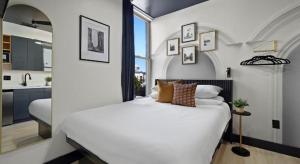 Un dormitorio con una gran cama blanca y una cocina. en Balboa Park Hotel Downtown Little Italy, en San Diego