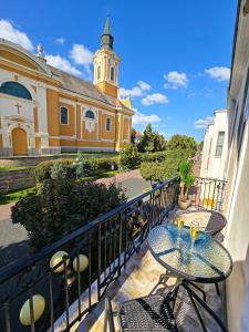 a balcony with tables and chairs and a church at Lumina Wellness Apartman in Sátoraljaújhely
