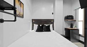 ein Schlafzimmer mit einem weißen Bett und schwarzen Kissen in der Unterkunft Balboa Park Hotel Downtown Little Italy in San Diego