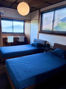 a bedroom with two beds and two chairs and windows at Vacation rental PIGGY's Nichinan in Nichinan
