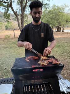 a man is cooking meat on a grill at The Yala Vista in Tissamaharama