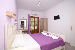 a white bedroom with a large bed with purple blanket at Sklavos Studios skopelos in Neo Klima