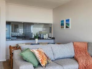 un salon avec un canapé et une cuisine dans l'établissement Dolphin Delight, à Bloubergstrand