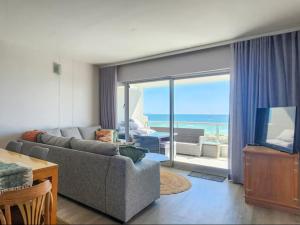 Il comprend un salon avec un canapé, une télévision et un balcon. dans l'établissement Dolphin Delight, à Bloubergstrand