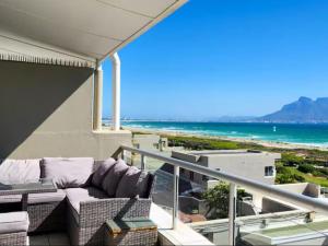 d'un balcon avec un canapé et une vue sur la plage. dans l'établissement Dolphin Delight, à Bloubergstrand