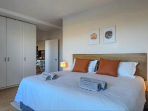 une chambre avec un grand lit blanc avec des serviettes dessus dans l'établissement Dolphin Delight, à Bloubergstrand