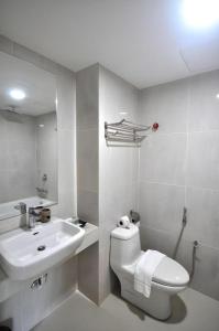 a white bathroom with a toilet and a sink at Hotel Scholar's Suites in Tanjung Malim