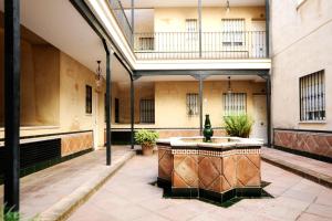 einen Innenhof mit einem Brunnen in der Mitte eines Gebäudes in der Unterkunft HSH Suites Corrala Triana in Sevilla