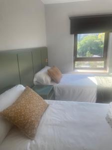two beds in a hotel room with a window at Entrenogueras in Huerta del Marquesado