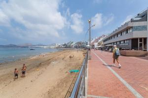 a man walking along a beach with people on it at El Rincon de Marta in Las Palmas de Gran Canaria