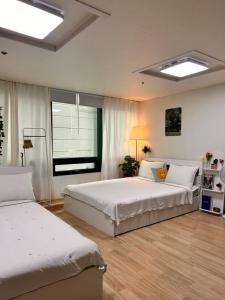 - une grande chambre avec 2 lits et une fenêtre dans l'établissement If House Hongdae, à Séoul