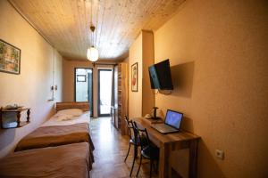 a room with two beds and a desk with a laptop at Hotel History in Kutaisi
