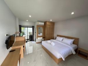 a bedroom with a large white bed and a television at J2 Airport Mansion in Thalang